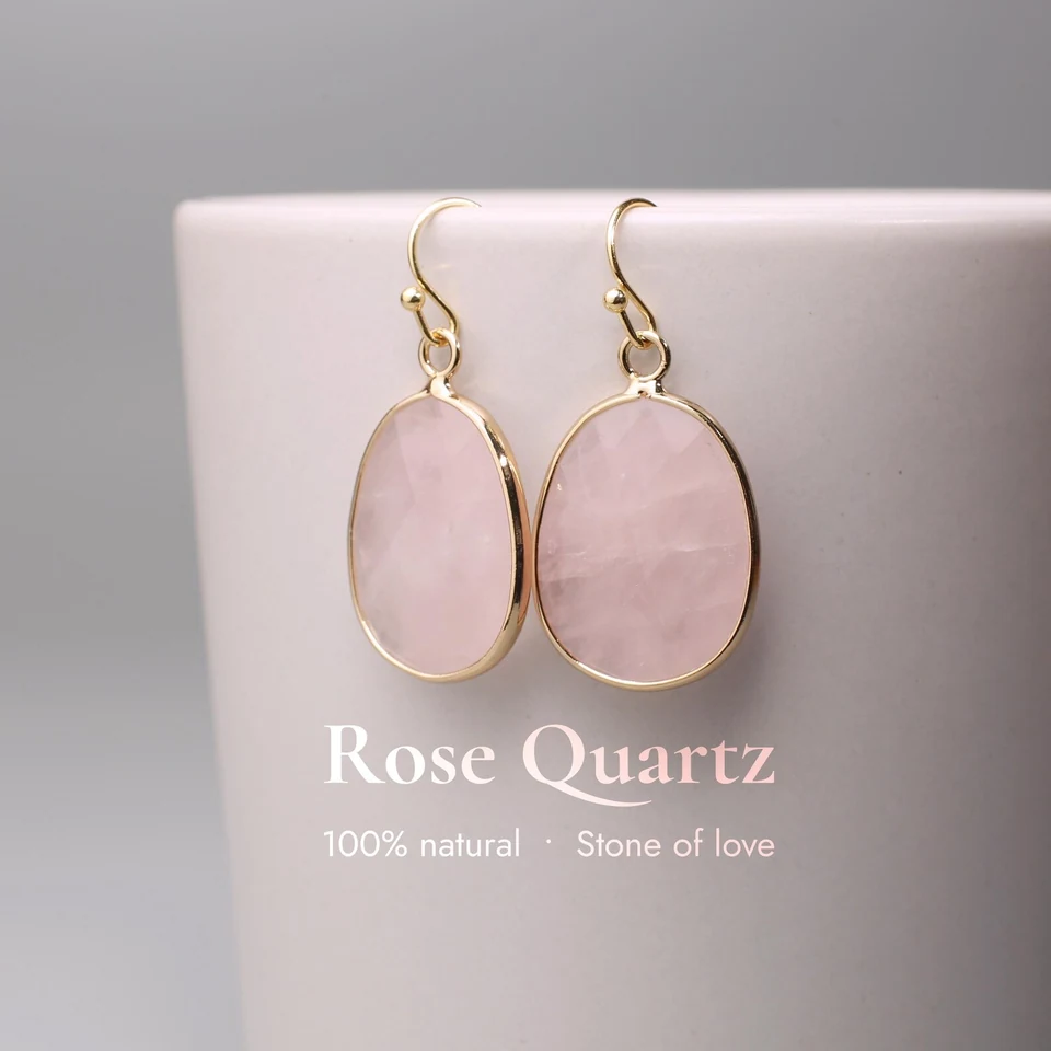 Faceted teardrop-like rose quartz drop earrings on a neutral display cup.